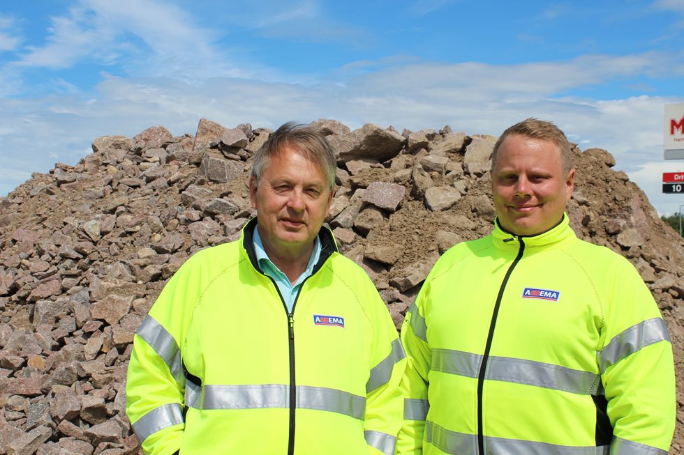 Two men posing in front of a rock pile at Abbema site. 