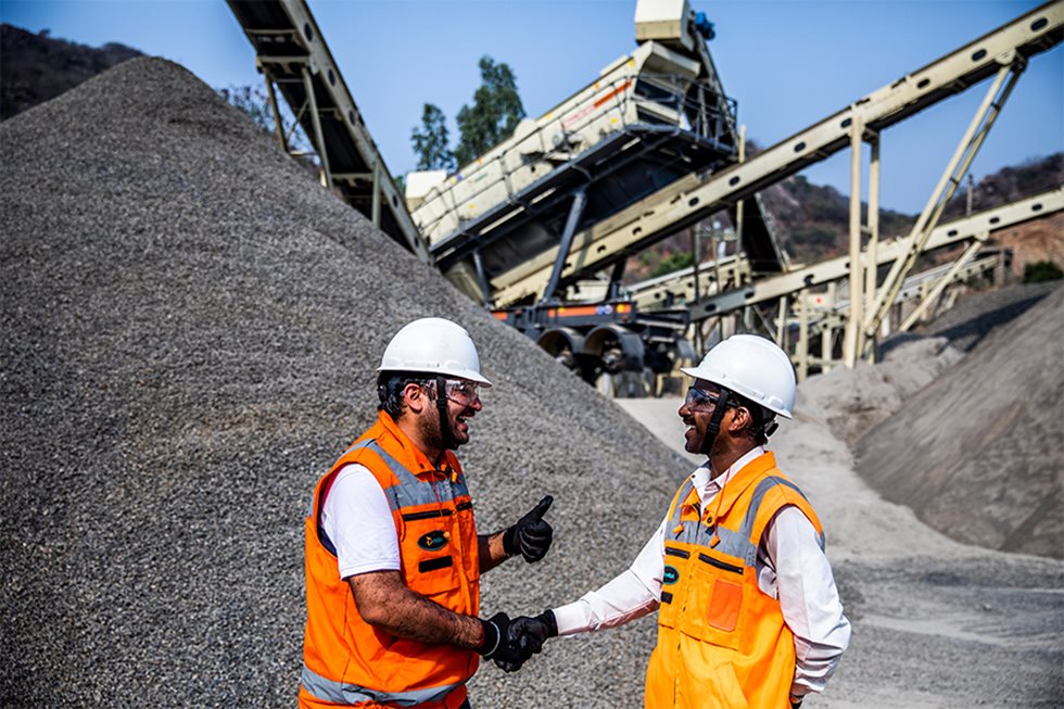 Two men shaking hands and laughing at a quarry. 